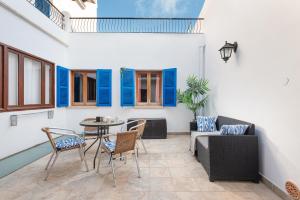 un patio con mesa, sillas y persianas azules en Sunset Cas Sastre, en Alcudia