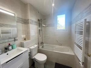 a bathroom with a toilet and a tub and a sink at Appart Laffitte joli T2 au coeur du parc & parking & RER pour Paris & La Défense in Maisons-Laffitte