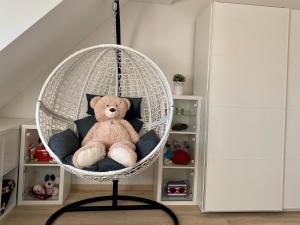 un ours en peluche assis sur une balançoire dans une pièce dans l'établissement gemütliches Dachgeschoss, à Bonn