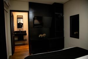 ein Schlafzimmer mit einem schwarzen Schrank mit einem Waschbecken und einem Spiegel in der Unterkunft Pousada Serra & Jardim in Bom Jardim da Serra