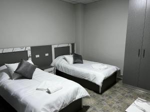 a room with two beds with white sheets at Downtown Inn Madaba in Madaba