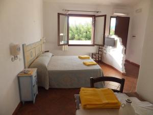 um quarto com 2 camas, uma mesa e uma janela em Grazia Deledda em Galtellì
