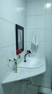 La salle de bains blanche est pourvue d'un lavabo et d'un miroir. dans l'établissement Casa para temporada, à Porto Seguro