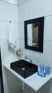 La salle de bains est pourvue d'un lavabo noir et d'un miroir. dans l'établissement Casa para temporada, à Porto Seguro
