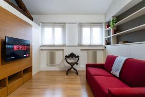 un soggiorno con divano rosso e TV di Antica dimora sul Naviglio a Gaggiano