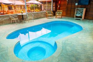 a blue swimming pool with a table and chairs at Pousada Serra Villena in Monte Verde