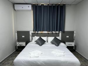 a bedroom with a large white bed with two pillows at Downtown Inn Madaba in Madaba