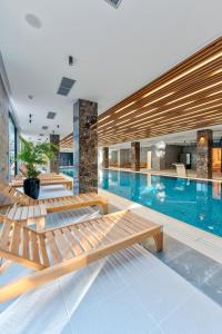 a swimming pool with wooden benches in a building at Queen of Zlatibor in Zlatibor