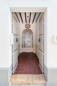 einen leeren Flur mit weißen Türen und Ziegelboden in der Unterkunft La Casa del Convento in Villamanrique de la Condesa