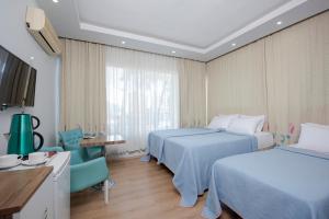 a hotel room with two beds and a chair at Gvar Hotel ANTALYA in Antalya