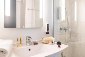 uma casa de banho branca com um lavatório e um chuveiro em B&B HOTEL Lyon Eurexpo Bron em Bron