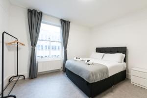 a bedroom with a large bed and a window at Luxury 2 Bedroom Flat in Balcombe Street in London