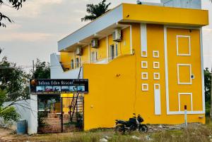 un edificio amarillo con una motocicleta estacionada frente a él en Selvas Eden Resort with river view near boat house, en Pondicherry