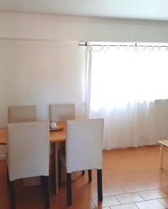 mesa de comedor con 2 sillas blancas y ventana en Depto de 2 Amb - 4 Pax - B San José en Mar del Plata