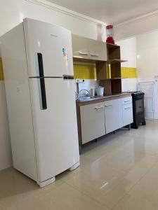 a large white refrigerator in a kitchen at Maria Rosa Aparts in Matinhos