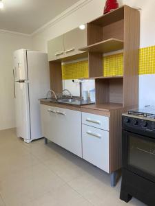 a kitchen with white cabinets and a refrigerator at Maria Rosa Aparts in Matinhos