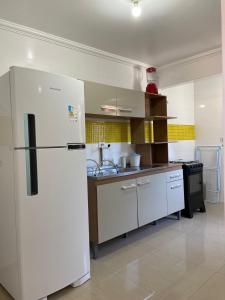 a kitchen with a white refrigerator in a room at Maria Rosa Aparts in Matinhos