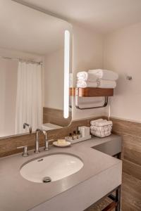 a bathroom with a sink and a mirror and towels at Aviator Hotel Anchorage in Anchorage