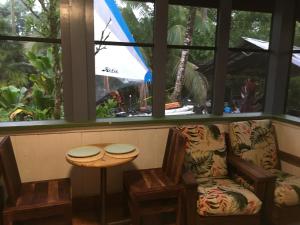 um quarto com uma cadeira, uma mesa e uma janela em The Hawaii Red House Apartment Private em Keaau