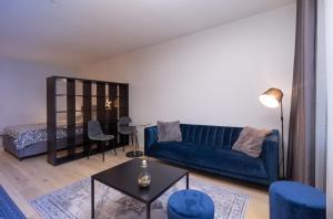 Revalia Das Haus Studios في تالين: غرفة معيشة مع أريكة زرقاء وطاولة