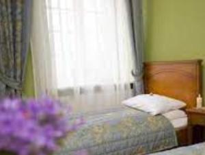 a bedroom with a bed with a window and purple flowers at Pałac Borowa in Borowa