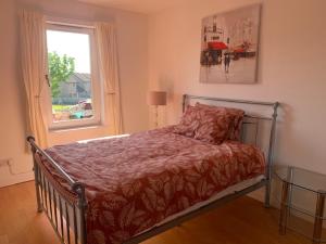 a bed in a bedroom with a window and a bedspread at Modern One Bedroom Apartment in Lossiemouth