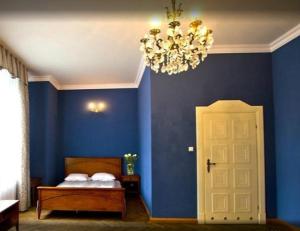 a blue bedroom with a bed and a chandelier at Pałac Borowa in Borowa