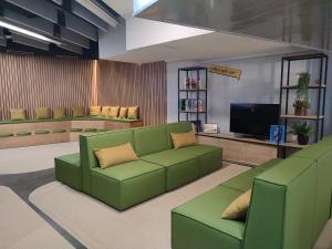 a living room with a green couch and a tv at Twentytu Hostel Barcelona in Barcelona