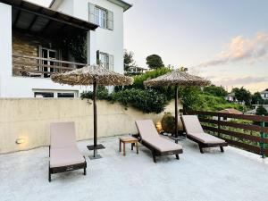 grupa krzeseł i parasoli na patio w obiekcie Luxury Villa at Pelion- Ruby w mieście Zagora