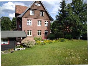 una gran casa de ladrillo con un campo verde delante de ella en Gästehaus Mea Vota en Braunlage
