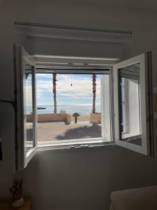 ein offenes Fenster mit Blick auf den Strand in der Unterkunft Casita La Basseta d’ Oli in Villajoyosa