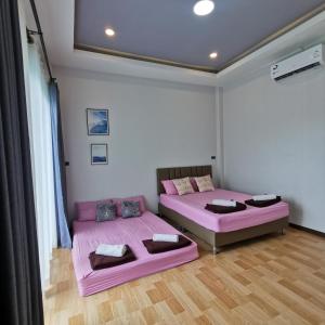 two beds in a room with pink sheets at ภูริญาพู​ลวิลล่า in Sattahip