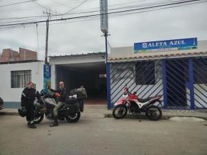 dos hombres sentados en motocicletas delante de un garaje en Qaleta Azul en Camaná