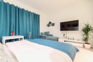 - une chambre avec des rideaux bleus, un lit et une télévision dans l'établissement Galerija Libera, à Belgrade