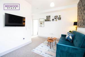 sala de estar con sofá azul y mesa en Modern 1 Bed 1 Bath Apartment for Corporates & Contractors, FREE Parking, Wi-Fi & Netflix By REDWOOD STAYS en Farnborough
