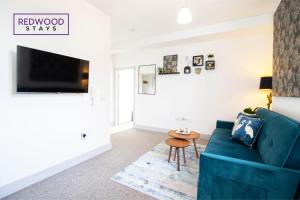 a living room with a blue couch and a table at Modern 1 Bed 1 Bath Apartment for Corporates & Contractors, Free Parking, Wi-Fi & Netflix By Redwood Stays in Farnborough
