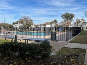 a fence with two picnic tables in front of a pool at Studio 6 Mesquite, TX Town East in Mesquite