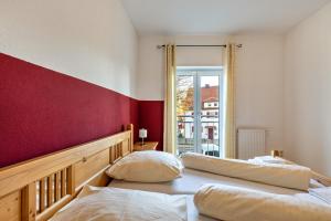 2 camas en una habitación con una pared roja en Ferienwohnung Rechts, en Welden