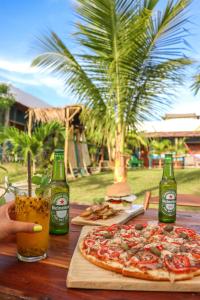 Back to the Beach Hostel - Pipa في بيبا: بيتزا على طاولة خشبية مع زجاجات من البيرة