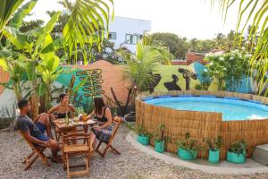 Back to the Beach Hostel - Pipa في بيبا: مجموعة من الناس يجلسون على طاولة بجانب المسبح