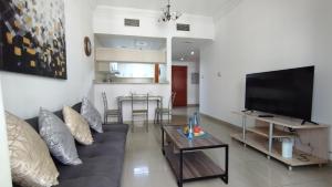 a living room with a couch and a flat screen tv at Marina View Manchester tower in Dubai