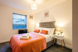 a bedroom with a bed with orange sheets and a window at Stylish 2 Bed City Centre Apartment with Sofa Bed - FREE Parking, Espresso Machine, Netflix, Alexa in Sheffield
