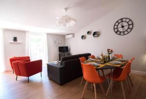 a living room with a table and a couch and a clock at Le Saint Gimer - Vue sur la Cité Médiévale - Climatisation in Carcassonne