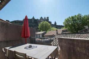 a table with a red umbrella on a balcony with a castle at Le Saint Gimer - Vue sur la Cité Médiévale - Climatisation in Carcassonne