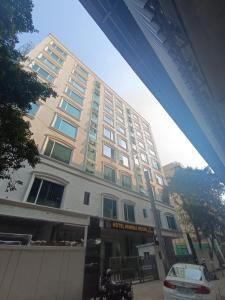 a large white building with a parking lot in front of it at Hotel Mumbai House, Valnai Malad in Mumbai
