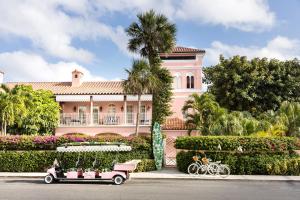 uma casa cor-de-rosa com um carrinho de golfe à frente. em The Colony Hotel em Palm Beach