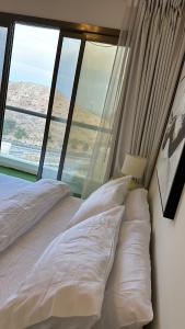 a bed with white pillows in a room with a window at City Gem - Qurm in Muscat