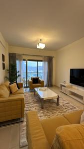 City Gem - Qurm في مسقط: غرفة معيشة مع كنبتين وتلفزيون