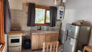 a small kitchen with a refrigerator and a sink at Cabaña SANTA MONTAÑA in Ushuaia