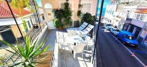 a balcony with tables and chairs on a city street at Sea Breeze Villa - in front of the beach in Câmara de Lobos